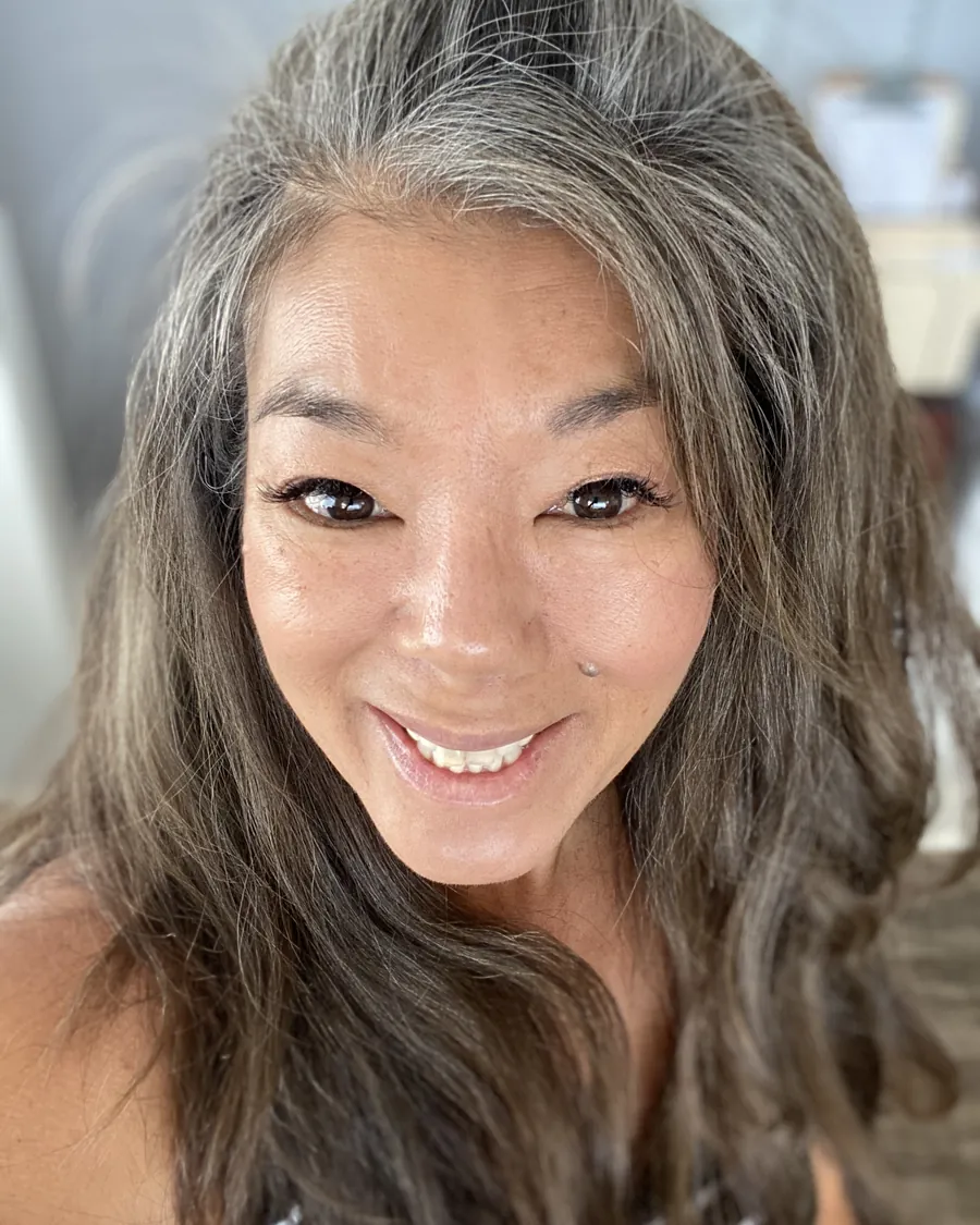 Portrait of Avis R. Takakura, smiling, with long silver hair.